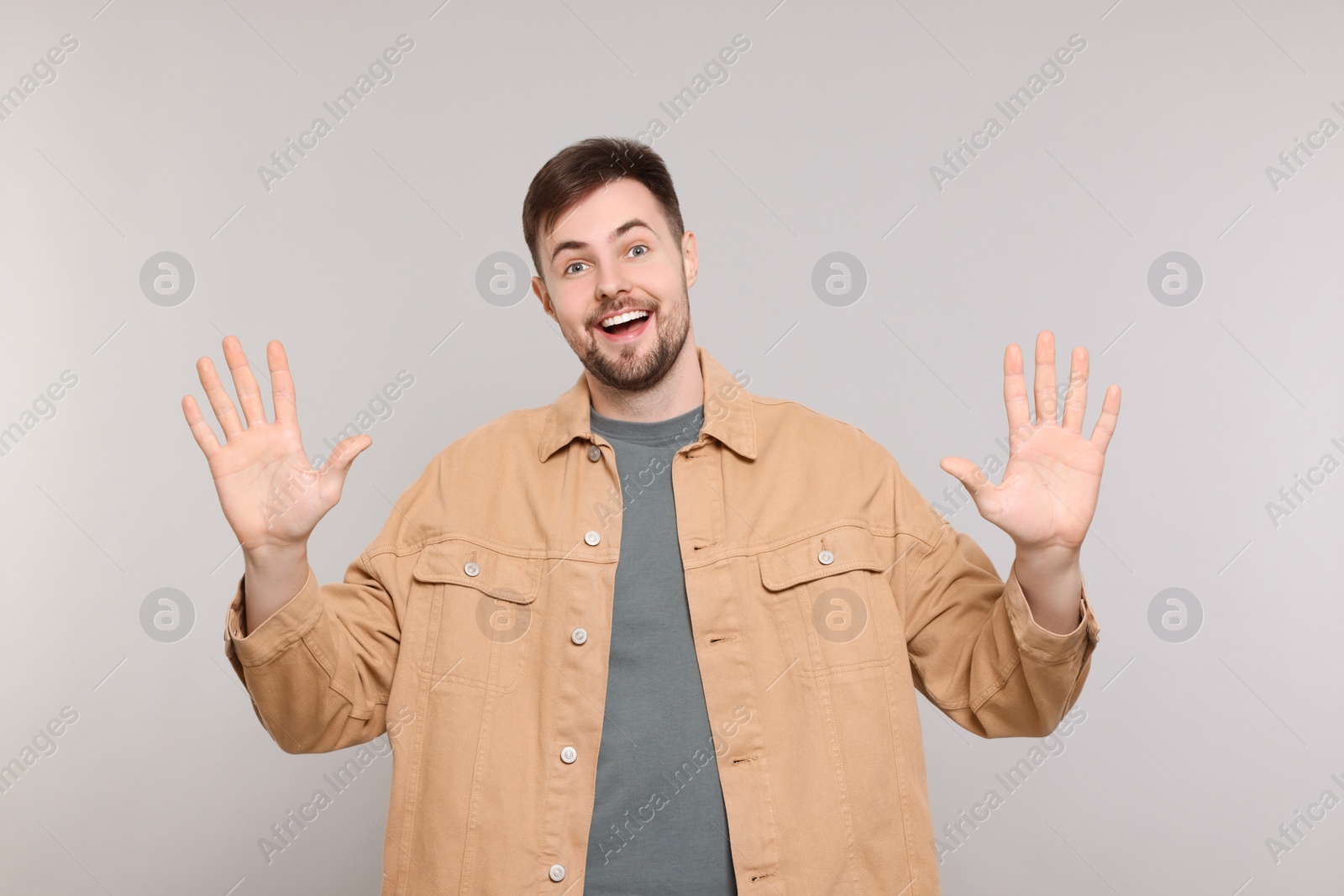 Photo of Man giving high five with both hands on grey background