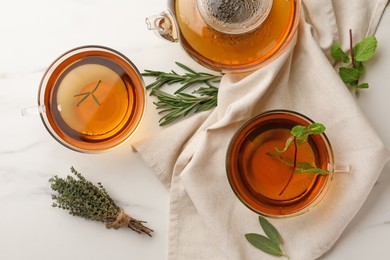 Photo of Aromatic herbal tea with rosemary, sage, thyme and mint on white marble table, flat lay