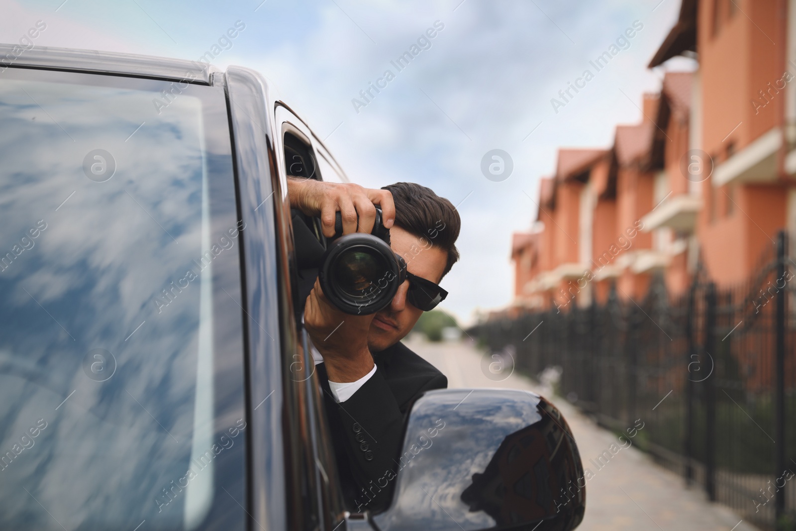 Photo of Private detective with camera spying from car