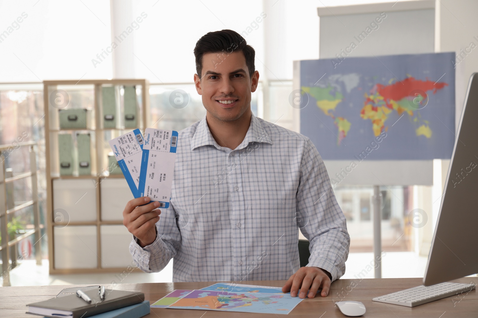 Photo of Travel agent with tickets at table in office