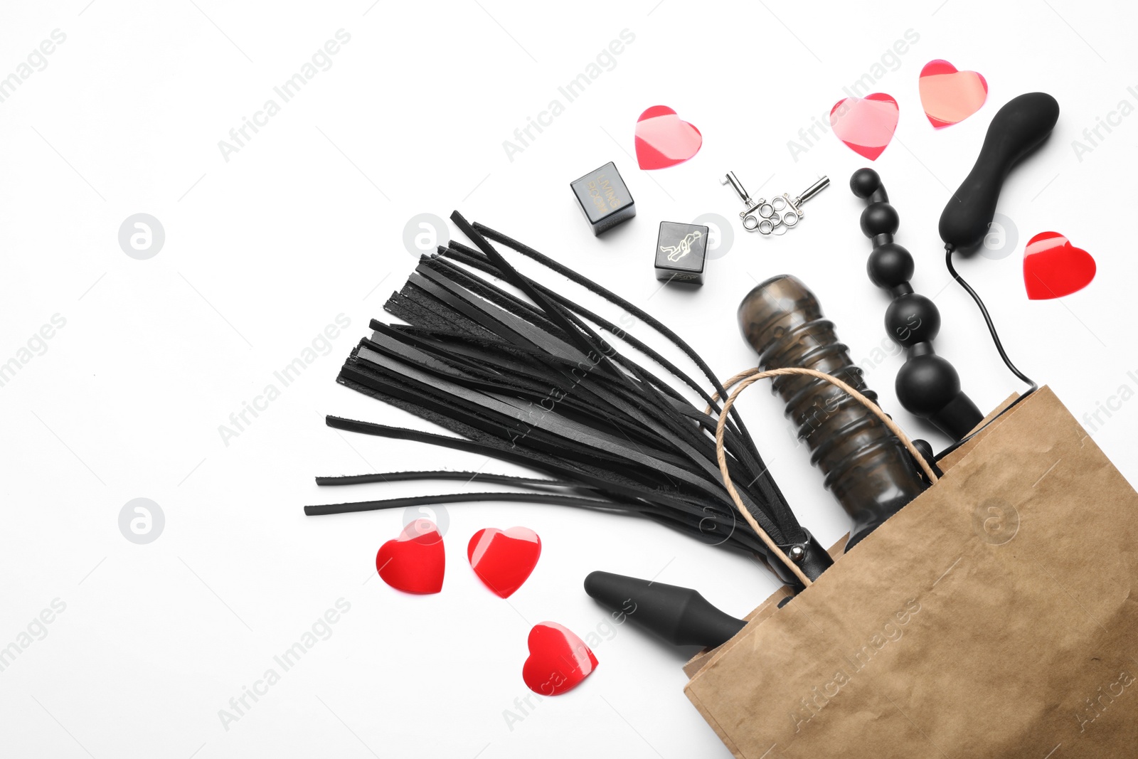 Photo of Paper shopping bag with different sex toys on white background, top view