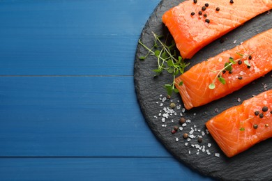 Photo of Fresh raw salmon and spices on blue wooden table, top view. Space for text