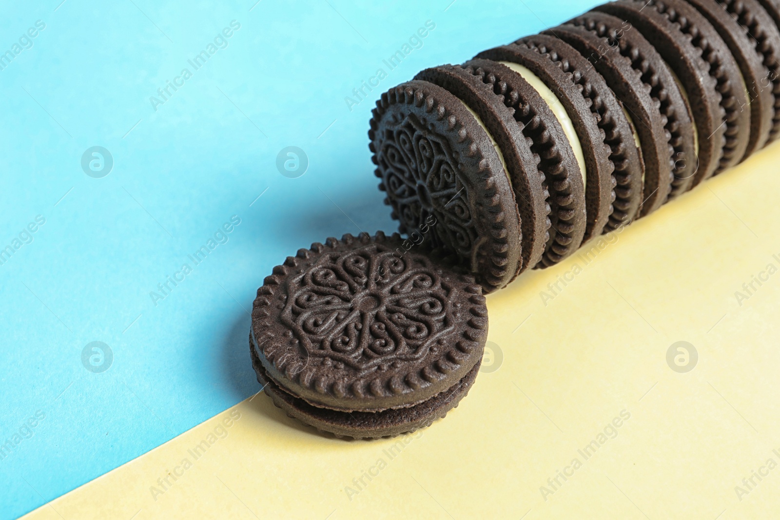 Photo of Tasty chocolate cookies with cream on color background. Space for text