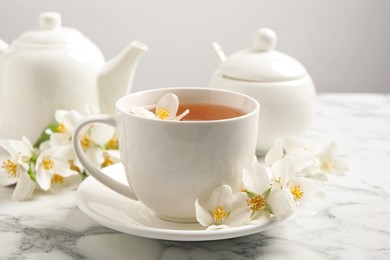 Aromatic jasmine tea and fresh flowers on white marble table