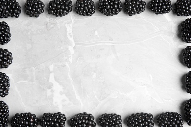 Photo of Frame made of tasty blackberries on grey marble table, top view with space for text