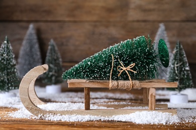 Sleigh with decorative Christmas tree on wooden table
