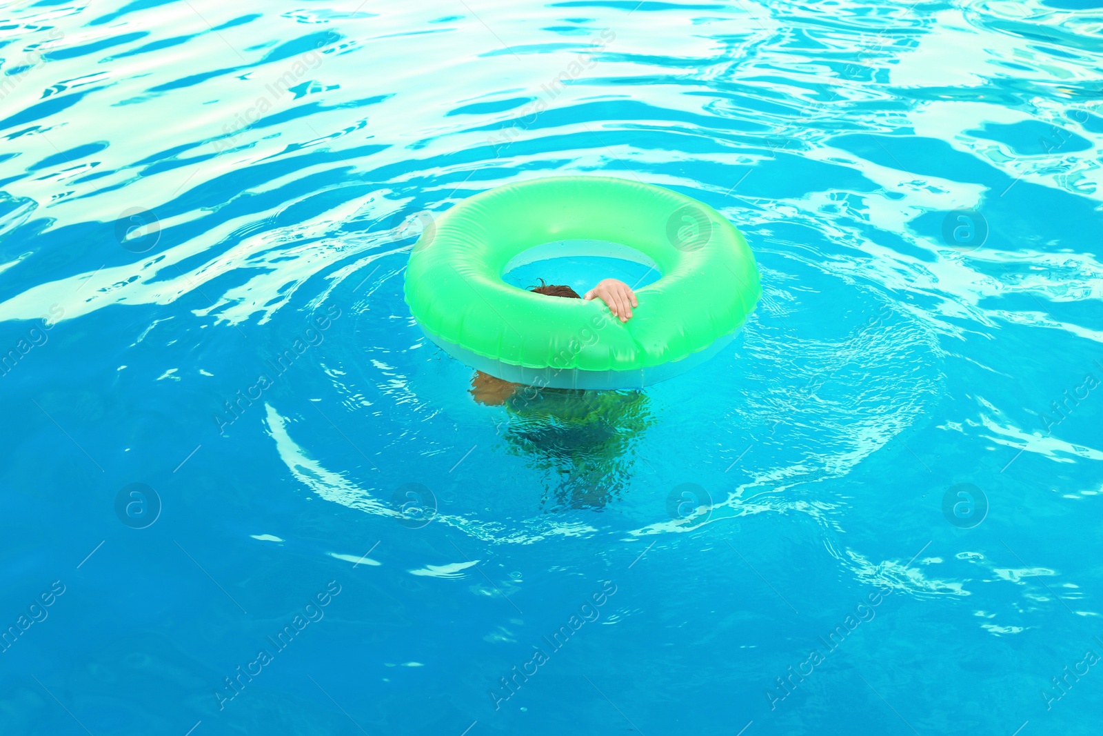 Photo of Little child with inflatable ring in outdoor swimming pool. Dangerous situation