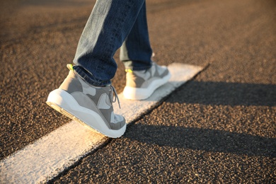 Man walking along white line on road, closeup with space for text. Way concept