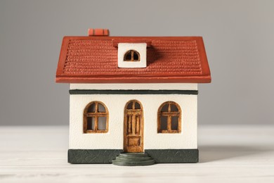 Photo of Mortgage concept. House model on white wooden table against grey background