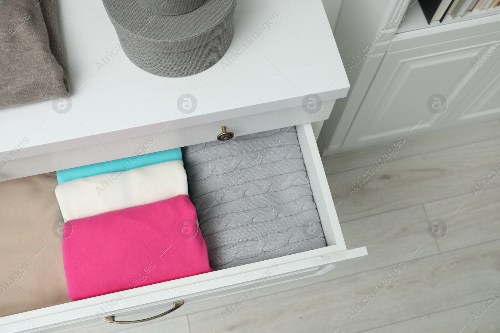 Photo of Chest of drawers with different folded clothes indoors, top view