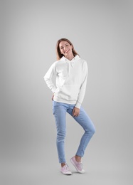 Full length portrait of woman in hoodie sweater on light background. Space for design