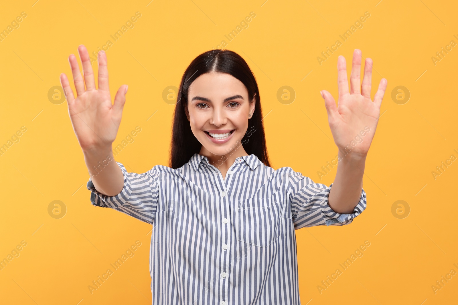Photo of Happy woman giving high five with both hands on orange background