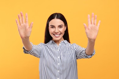 Photo of Happy woman giving high five with both hands on orange background