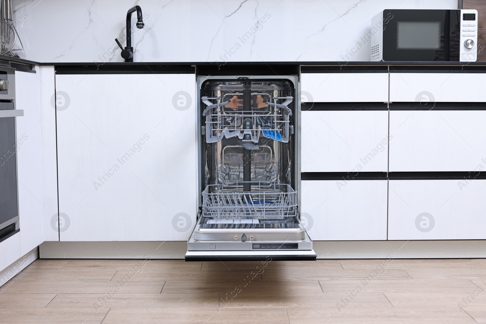 Photo of Open clean empty dishwasher in kitchen. Home appliance