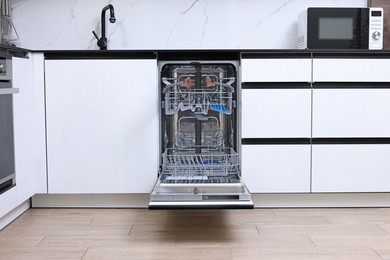 Photo of Open clean empty dishwasher in kitchen. Home appliance