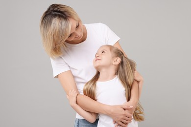 Family portrait of happy mother and daughter on grey background