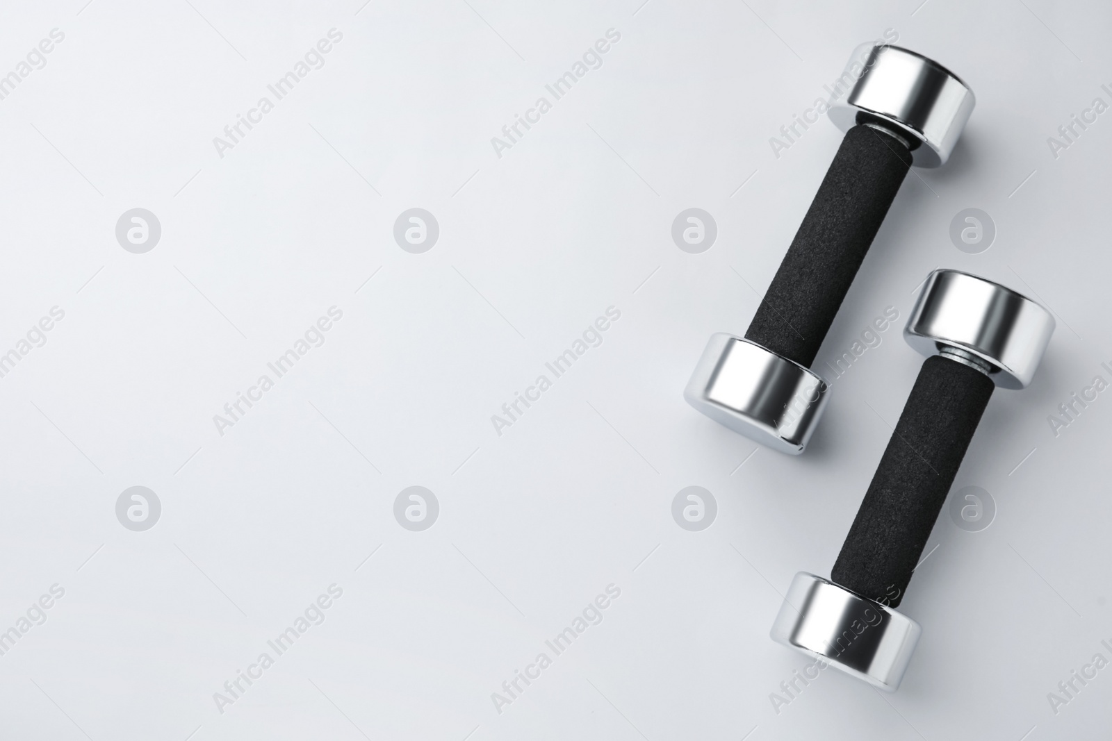 Photo of Metal dumbbells on light background, flat lay. Space for text