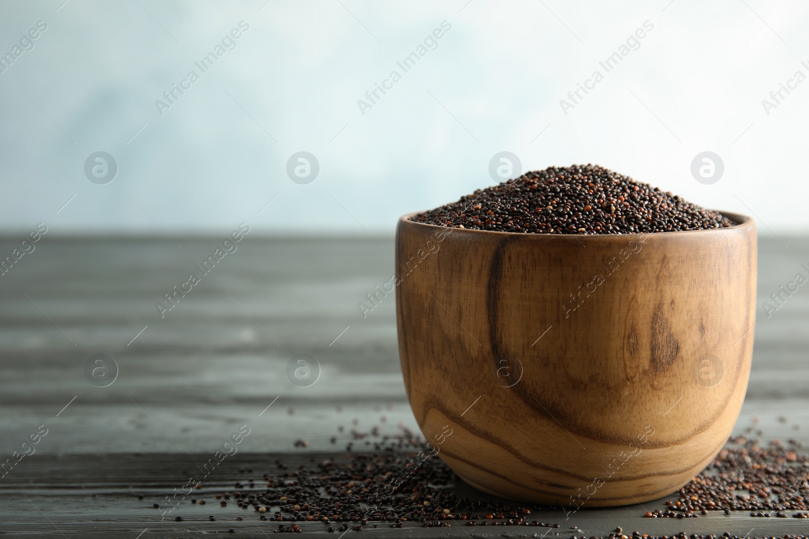 Photo of Bowl with black quinoa on wooden table. Space for text