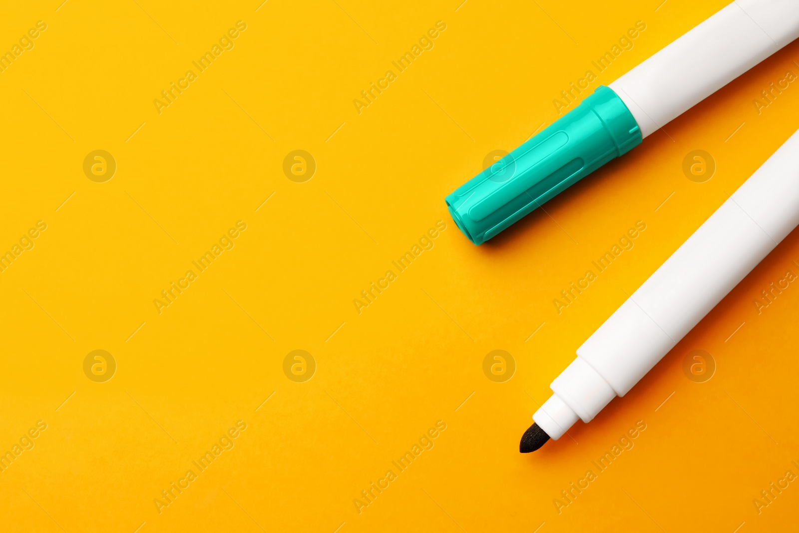 Photo of Bright color markers on orange background, flat lay. Space for text