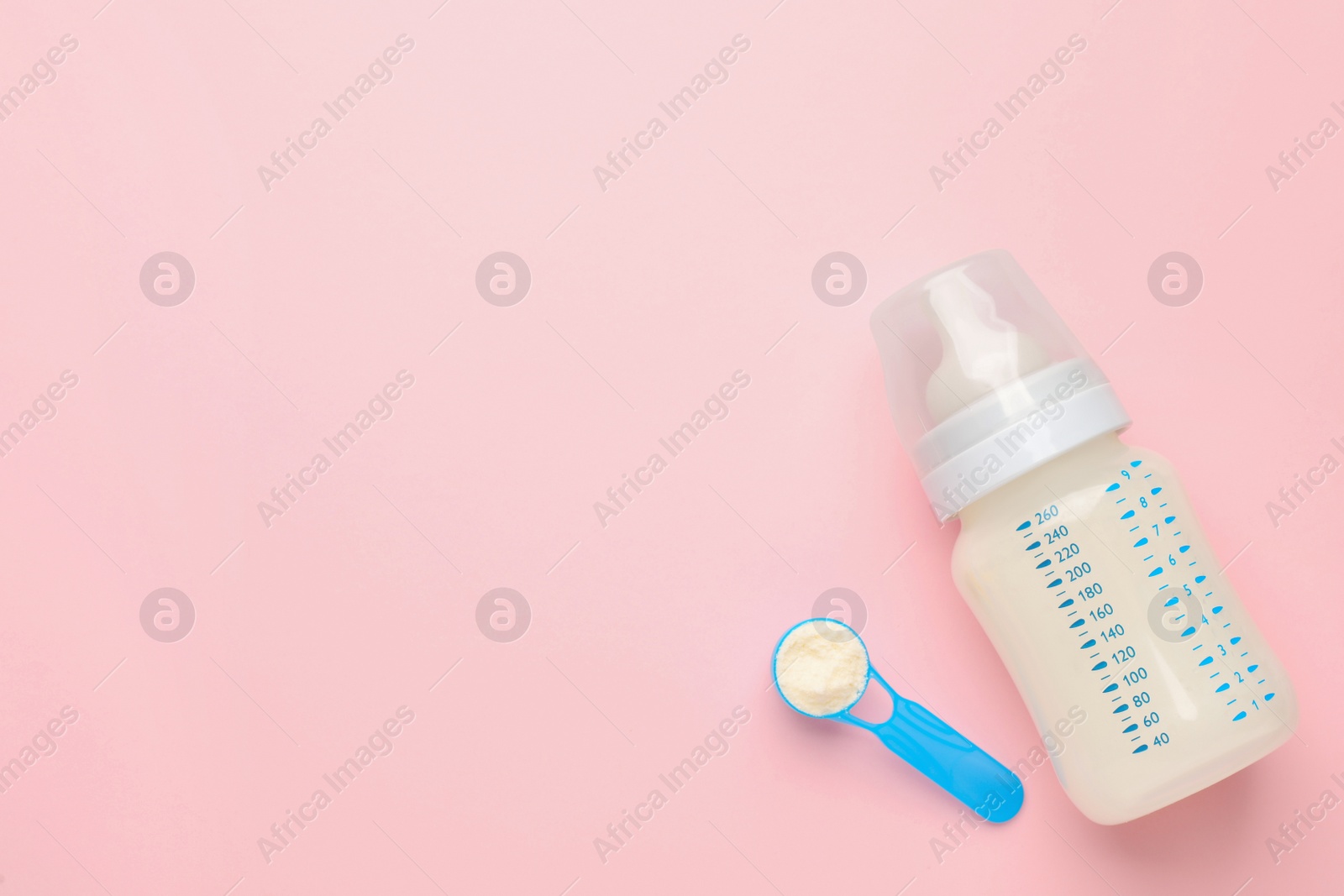 Photo of Feeding bottle with infant formula and powder on pink background, flat lay. Space for text