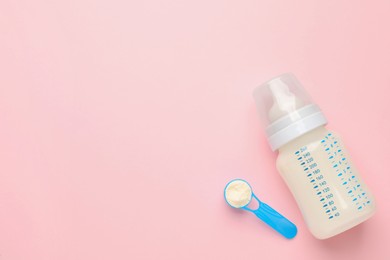 Feeding bottle with infant formula and powder on pink background, flat lay. Space for text