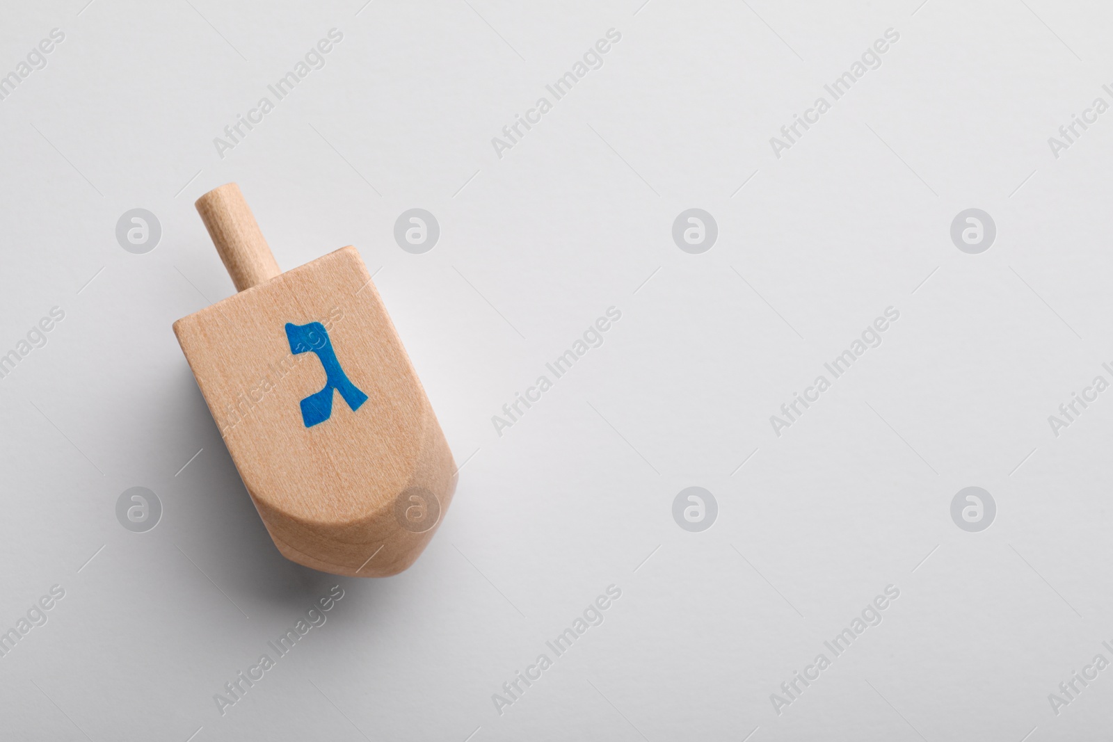 Photo of Wooden dreidel on white background, top view with space for text. Traditional Hanukkah game