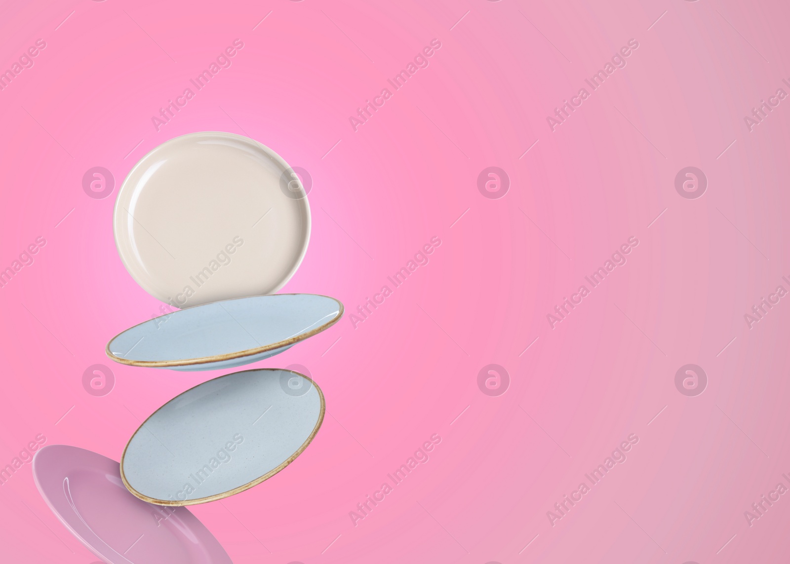 Image of Many different plates falling on pink gradient background, space for text