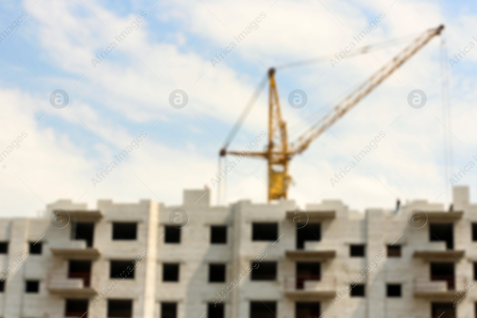 Photo of Blurred view of unfinished building and construction crane outdoors