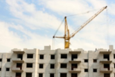 Photo of Blurred view of unfinished building and construction crane outdoors