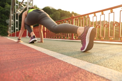 Photo of Sporty young woman stretching after running outdoors