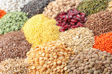 Photo of Different types of legumes and cereals as background, closeup. Organic grains
