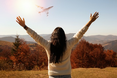 Woman in mountains under sky with flying airplane