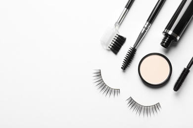 Photo of Composition with false eyelashes and other makeup products on white background, top view