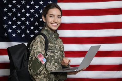 Photo of Female cadet with backpack and laptop against American flag. Military education