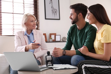 Female notary working with young couple in office