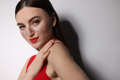 Photo of Beautiful woman with glitter freckles on light background