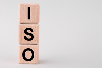 Photo of International Organization for Standardization. Cubes with abbreviation ISO on light grey background, closeup. Space for text