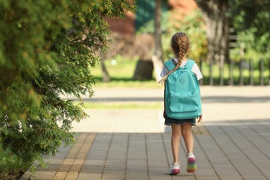 Photo of Little girl with backpack going to school, back view. Space for text