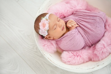 Photo of Adorable newborn girl lying in baby nest on light background