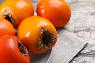 Photo of Delicious ripe persimmons on grey textured table, closeup