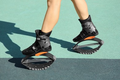 Woman with kangoo jumping boots in workout park, closeup