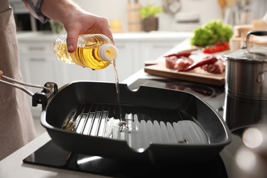 Photo of Man pouring cooking oil into frying pan in kitchen, closeup