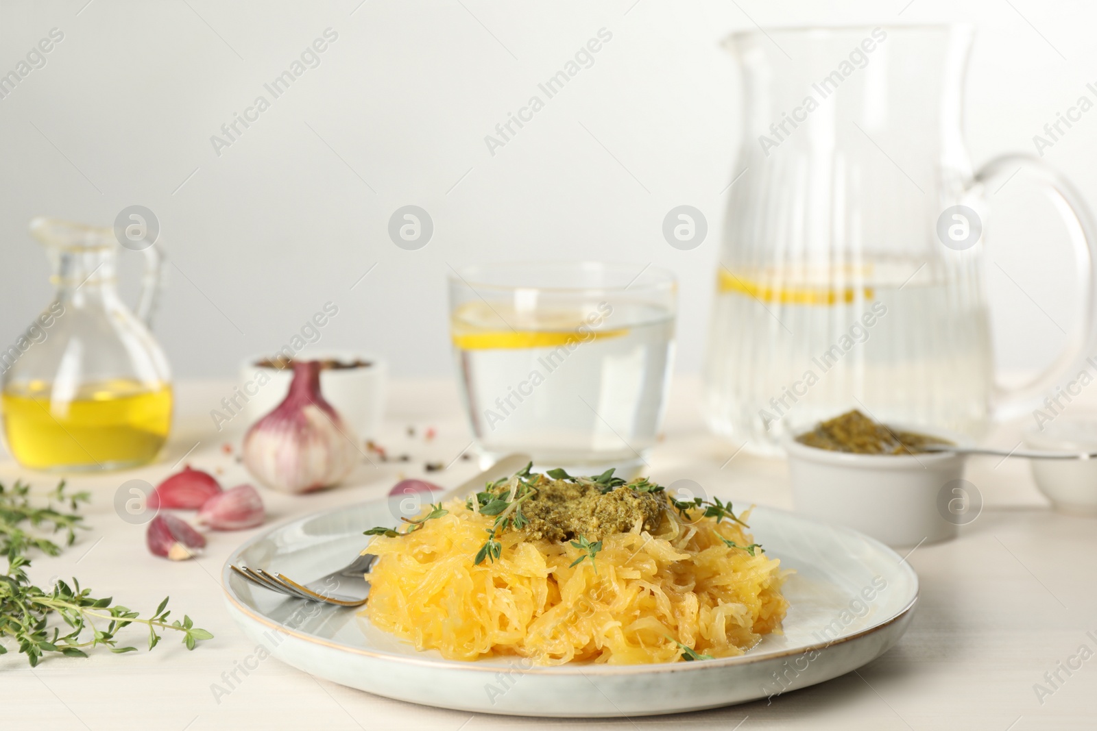 Photo of Tasty spaghetti squash with pesto sauce and thyme served on white wooden table