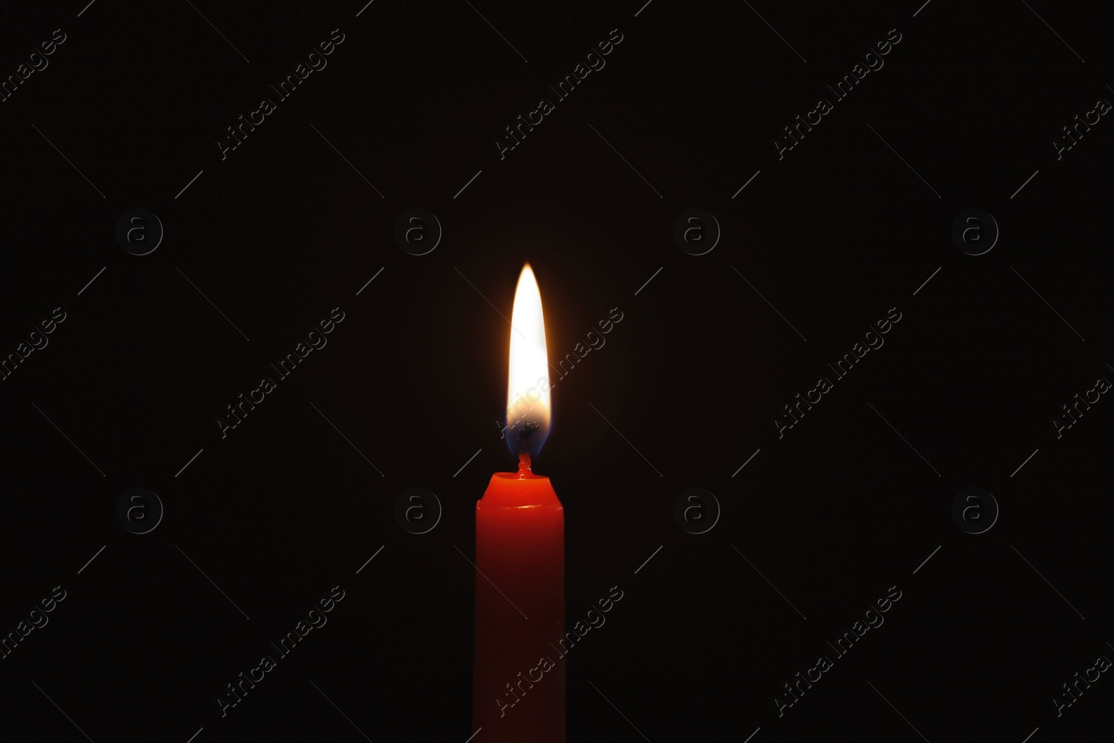 Photo of Wax candle burning on black background, closeup