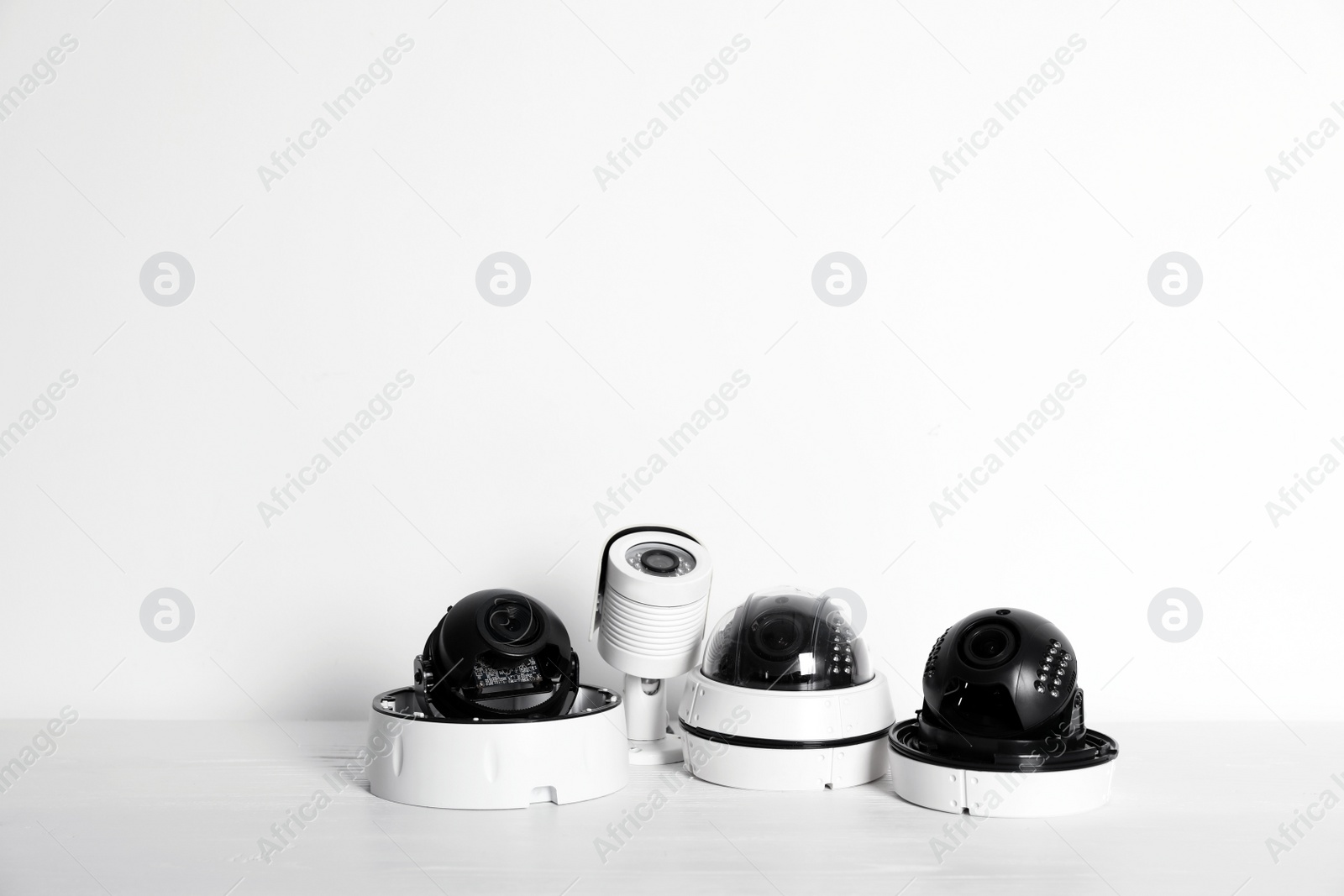 Photo of Modern CCTV cameras on table against light background. Home alarm system