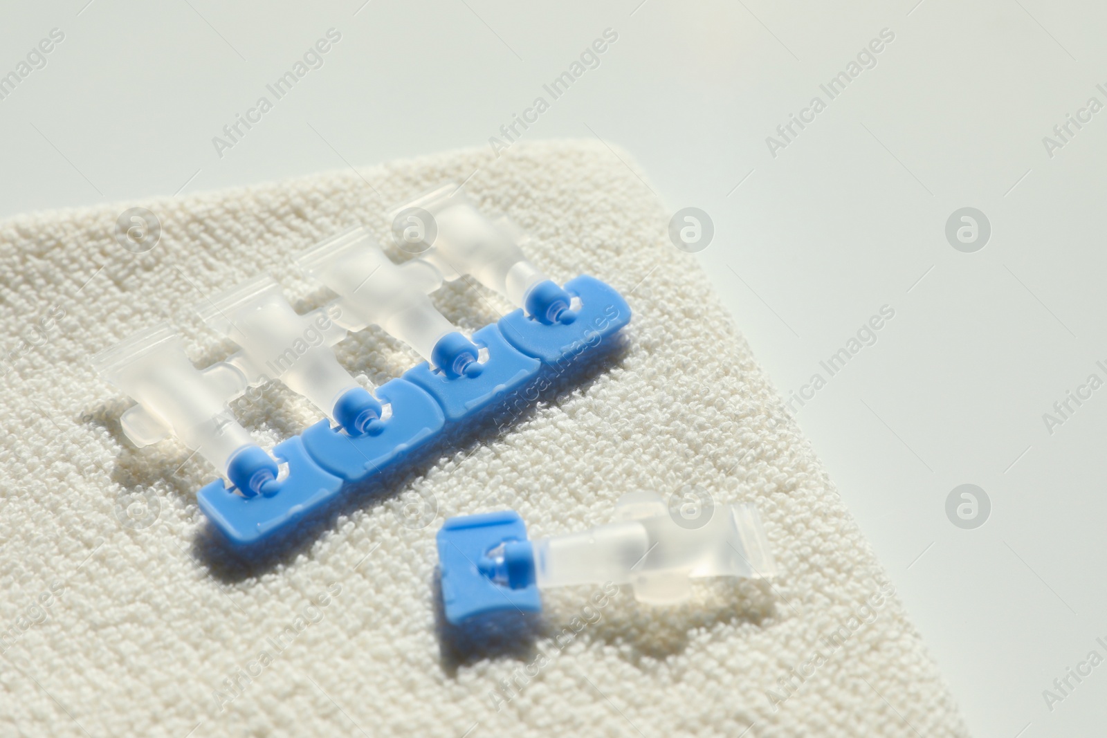 Photo of Single dose eye drops and towel on white table, closeup