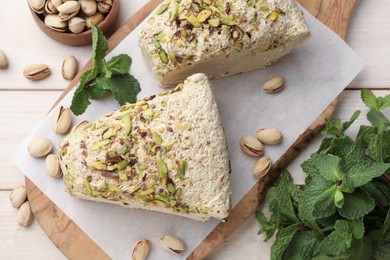 Photo of Pieces of tasty halva with pistachios and mint on table, flat lay
