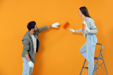 Man and woman painting orange wall. Interior design