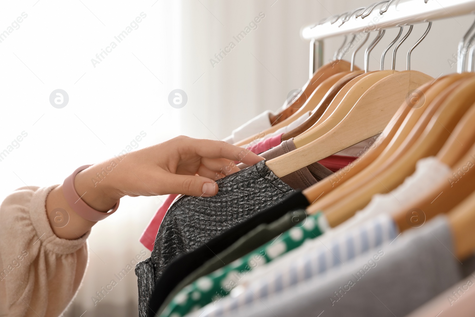 Photo of Woman choosing clothes from wardrobe rack, closeup