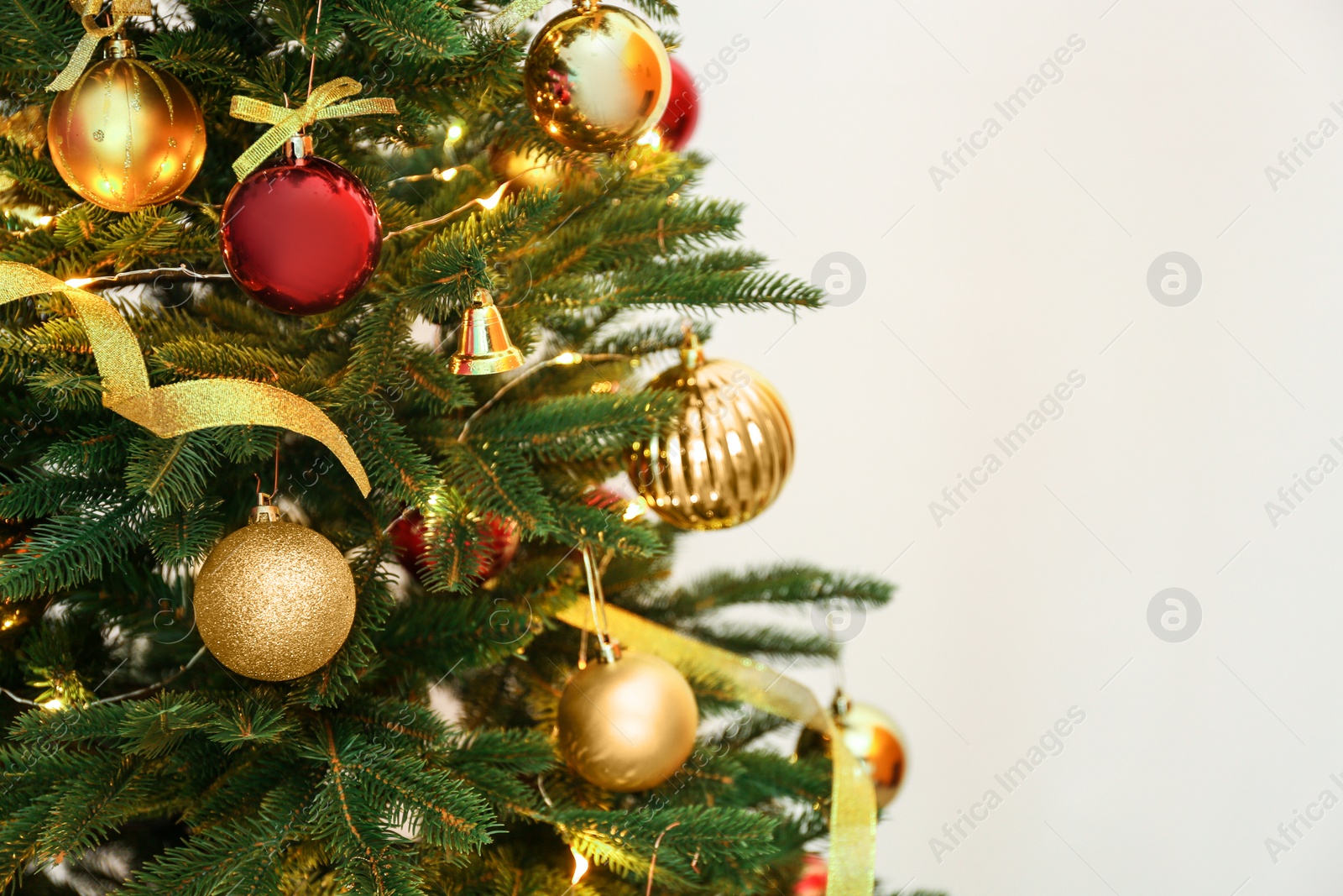 Photo of Beautiful Christmas tree with fairy lights and festive decor on color background